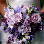 A Quinceanera holding a bouquet of purple and white flowers at her celebration