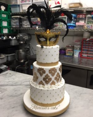 Quinceanera cake, a three tiered cake with a mask on top