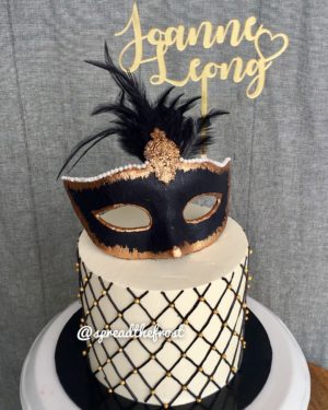 A Quinceanera birthday cake decorated with a mask on top
