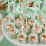 A plate of green and light pink Quinceañera dresses, cake pops decorated with flowers and leaves