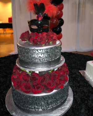 Quinceanera cake, a three-tiered cake with red roses, and a mask on top