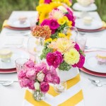 Quinceanera table decor with pink and yellow theme featuring plates and vases filled with flowers