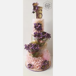 Quinceanera ceremony featuring a three-tiered cake adorned with purple flowers.