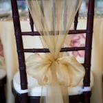 Quinceanera decoration ideas: A close up of a chair with a bow and chair sash