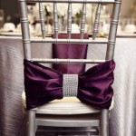 A Quinceanera venue decorated with wedding colors schemes. The white chair is adorned with a purple bow on top.