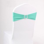 A turquoise table with a white chair adorned with a green bow tie for a Quinceanera celebration.