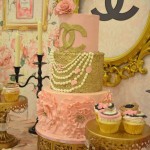 Cake decorating for a Quinceanera celebration, featuring a table topped with a pink and gold cake and cupcakes