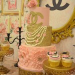 Cake decorating for a Quinceanera celebration, featuring a table topped with a pink and gold cake and cupcakes