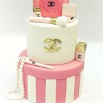 A pink and white Quinceanera cake with a Chanel bag on top