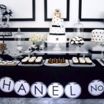 A Quinceanera celebration with a Chanel themed party. The image shows a table filled with various desserts and cupcakes.