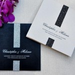 A black and white Quinceanera invitation with purple flowers on a table