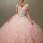 A woman in a pink ball gown posing for a Quinceañera picture