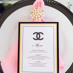 CHANEL, a black and white dinner plate with a pink napkin, perfect for a Quinceanera celebration