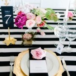A black and white striped table setting with gold chargers