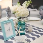 A Quinceanera-themed centrepiece table with a picture frame and a vase of flowers