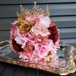 A beautiful floral design of a bouquet of flowers on a tray on a table, perfect for a Quinceanera celebration