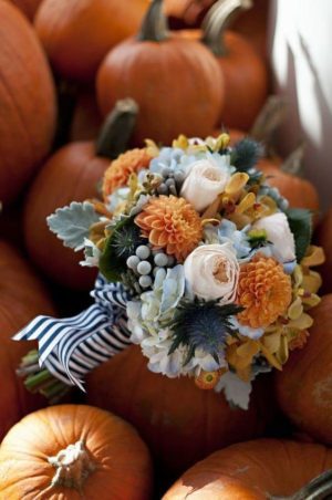 A Quinceanera bouquet of flowers sitting on top of a pile of pumpkins