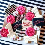 Quinceanera gift: a white plate topped with cookies covered in pink and black icing