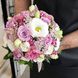 A man holding a bouquet of pink and white flowers with floral design