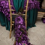 A Quinceanera-themed interior design table featuring a purple and green chair adorned with a peacock tail.