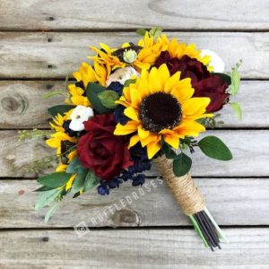 A Quinceanera bouquet of burgundy sunflowers and roses placed on a wooden table