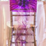 A lilac table with a chair adorned with a purple flower for a Quinceanera celebration