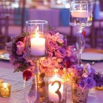 Quinceanera centerpiece with purple and gold details. A beautifully decorated table adorned with candles and flowers.