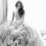 A woman in a Quinceanera dress sitting on a bed