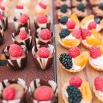 A variety of Quinceanera desserts, including petit fours, are displayed on a table.