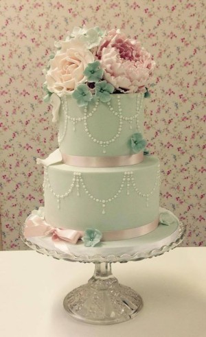 A pink and mint green Quinceanera cake, a three-tiered cake with flowers on top