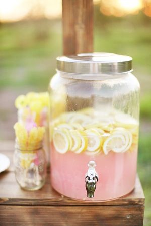 A Quinceanera-themed image featuring a pink lemonade dispenser filled with lemon slices