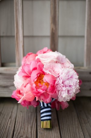 A Quinceanera-themed pink peony bouquet with navy blue ribbon, resting on a wooden floor