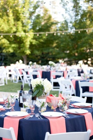 Quinceanera table decorations with navy blue and coral color scheme, featuring a table set up with white chairs and blue tablecloths