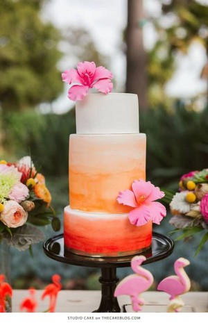 A Quinceanera cake with three tiers, decorated with pink and orange flowers on top