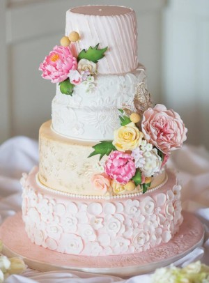 A three-tiered Quinceanera cake with pink and yellow flowers, perfect for a spring celebration.