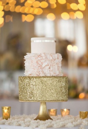 A Quinceanera cake, a white and gold sparkly wedding cake sitting on top of a table