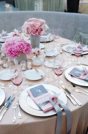 A Quinceanera themed table set for a formal dinner with pink flowers.