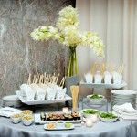 Quinceanera Asian food station featuring Thai cuisine, with plates of food displayed on a table alongside a vase of flowers.