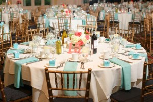 A table set up for a Quinceanera reception, with coral and Tiffany blue decorations.