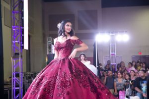 Quinceanera gown: A woman in a red dress walking down a runway