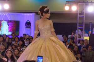 A Quinceanera fashion model wearing a gown, walking down the runway