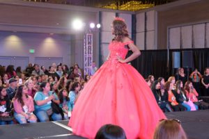 A woman in a pink Quinceanera dress walking down a runway in a Quinceanera fashion show T-shirt.