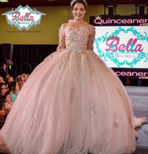 A woman in a Quinceanera ball gown, standing on a runway.