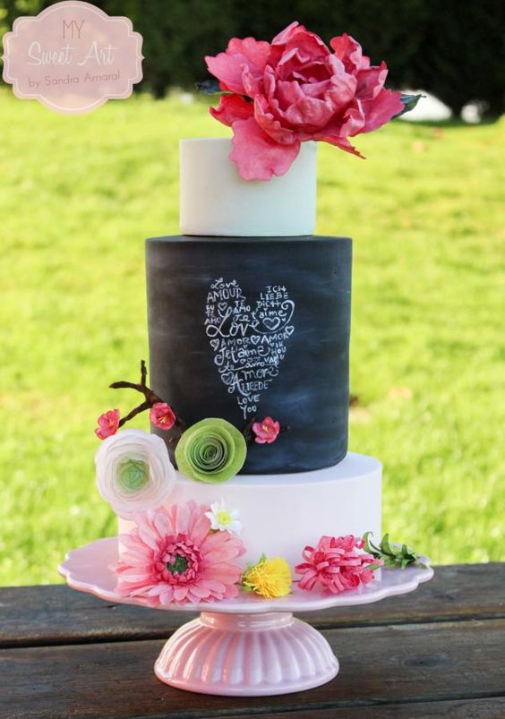 A Quinceanera cake, featuring a sugar cake with black and white design and pink flowers on top
