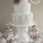 A lace vintage Quinceanera cake, a white Quinceanera cake and cupcakes on a table
