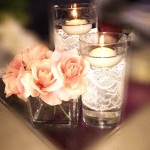 A Quinceanera themed centrepiece floral design featuring a couple of vases filled with flowers and candles