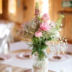 A quinceanera-themed flower bouquet table with a vase filled with flowers sitting on top of a table.