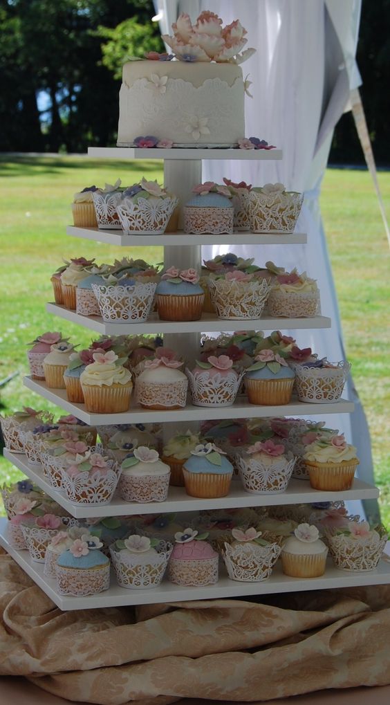 A Quinceanera themed buttercream cupcake on a three-tiered cake with additional cupcakes on top