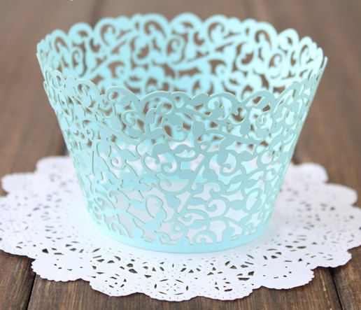 A blue cupcake wrapper with laser cutting placed on top of a doily for a Quinceanera celebration.