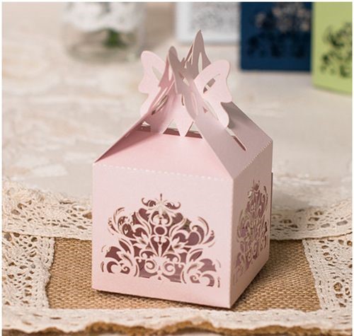 A small pink box with a bow on top of a table, containing a Quinceanera invitation